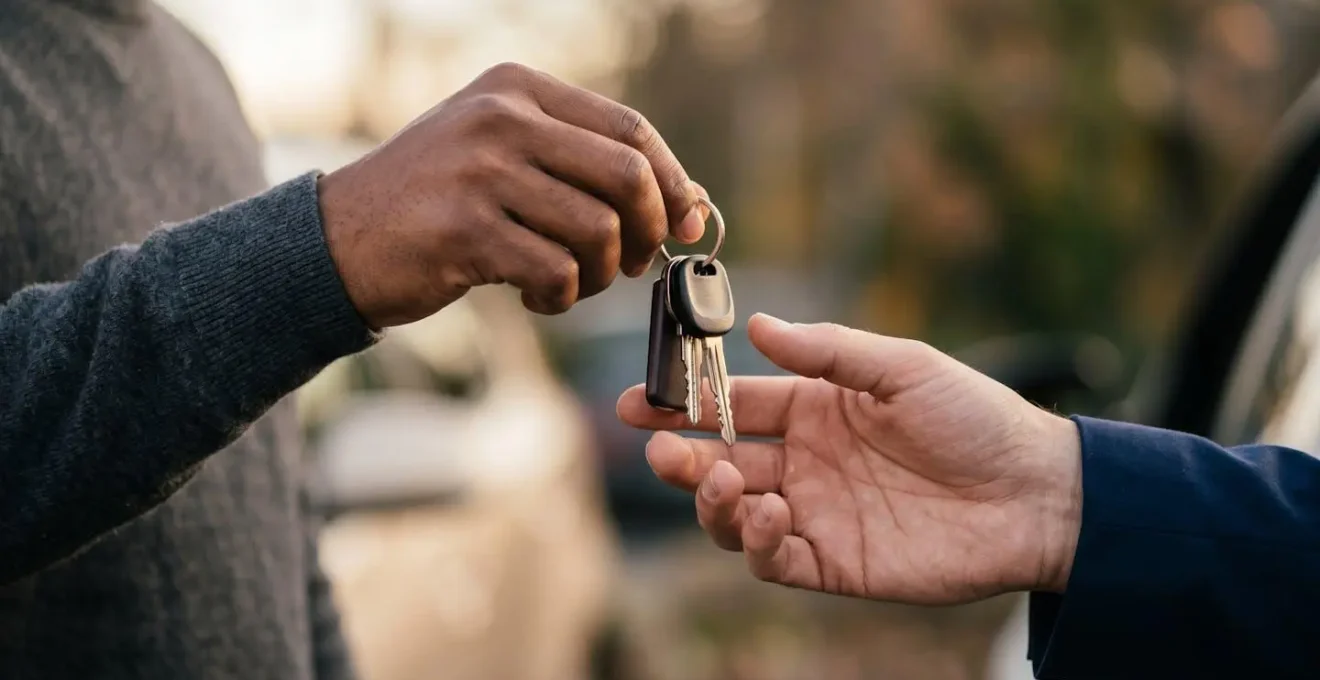 Échange de clés de voiture entre deux personnes symbolisant le prêt de volant et la confiance