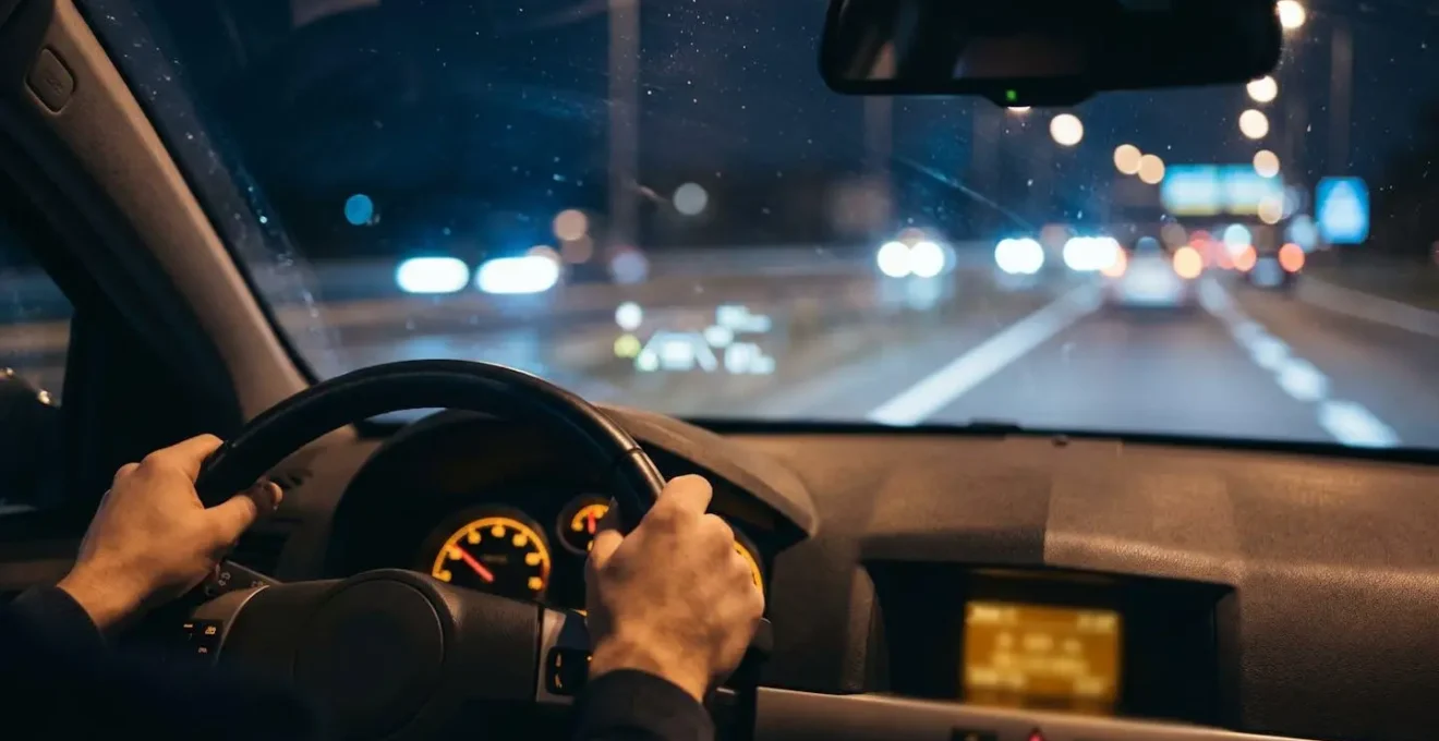 Volant moderne avec mains du conducteur et affichage tête haute ADAS sur pare-brise pendant conduite nocturne autoroutière